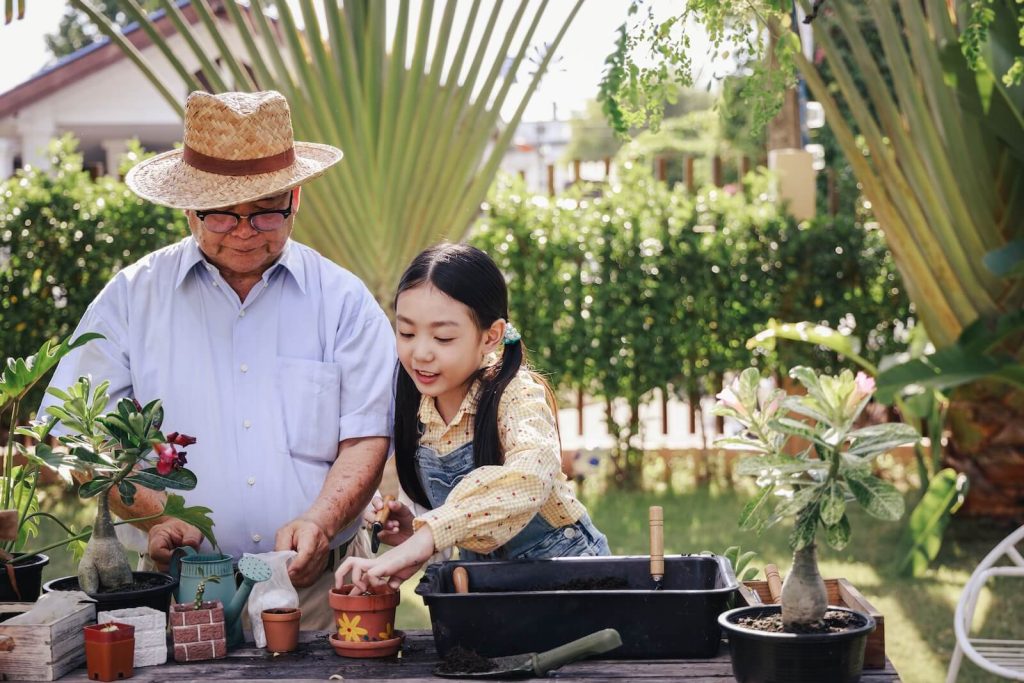This image shows a grandfather planting flowers with his granddaughter.