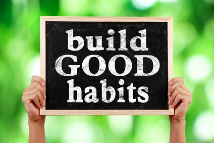 Person holding a chalkboard sign saying "Build Good Habits"