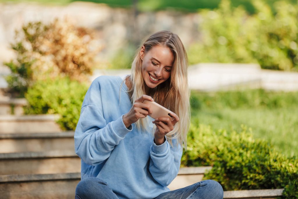 woman on park bench playing a game on her phone