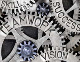 a set of interlocking gears with the different words written on each one, such teamwork, vision, success, and skill
