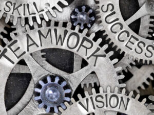 a set of interlocking gears with the different words written on each one, such teamwork, vision, success, and skill