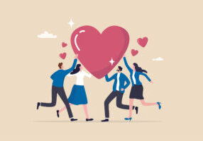 This image shows four businesspersons touching a heart to reflect teamwork and kindness.